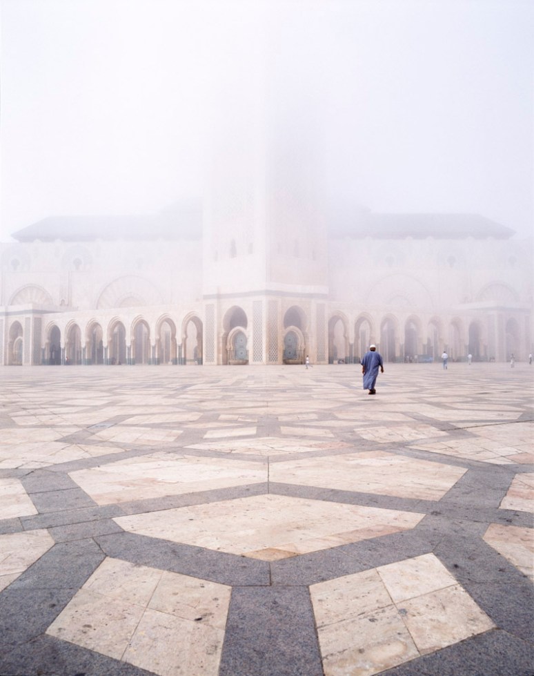 The Hassan II Mosque partially concealed by fog with a man wearing a Jalaba.