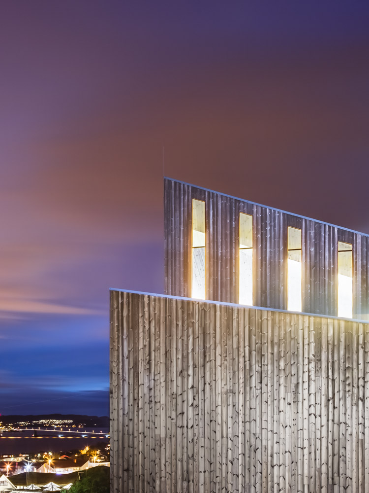 Window and cladding detail at night of Knarvik Church / Knarvik Kirke, Norway designed by Reiulf Ramstad Arkitekter.