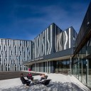 Young girl waving the Norwegian flag outside of a wave patterned Quality Hotel Edvard Grieg
